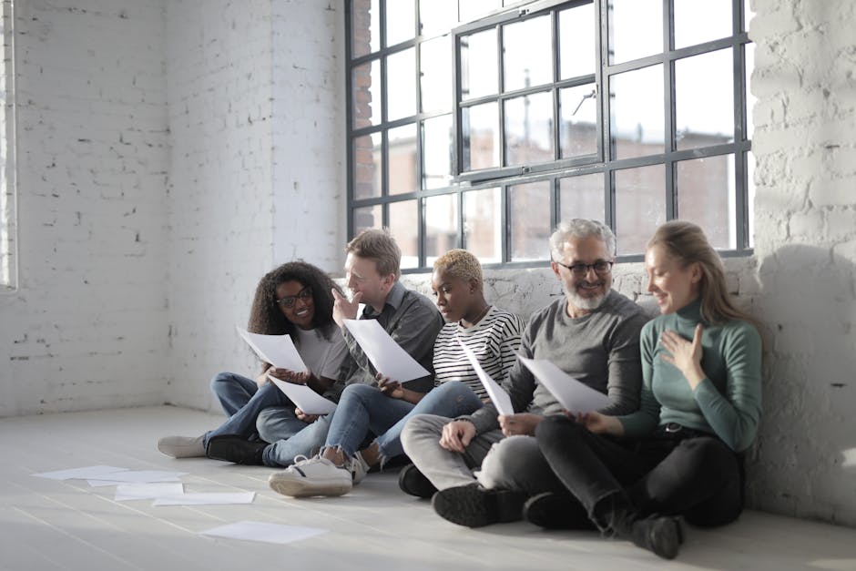 A diverse group of cheerful people sitting in yoga gear, chatting in a bright studio.